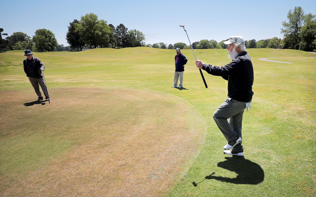 <strong>Lou Albonetti (right) reacts to a missed putt while Bill Sheppard (left) and Ray Duncan watch on from the edge of the green as golfers return to the Links at Whitehaven golf course on April 18, 2020, on a trial basis to test whether golfers would adhere to social distancing requirements during play. Only one person was permitted per cart and golfers were not allowed to handle the flag.</strong> (Jim Weber/Daily Memphian)