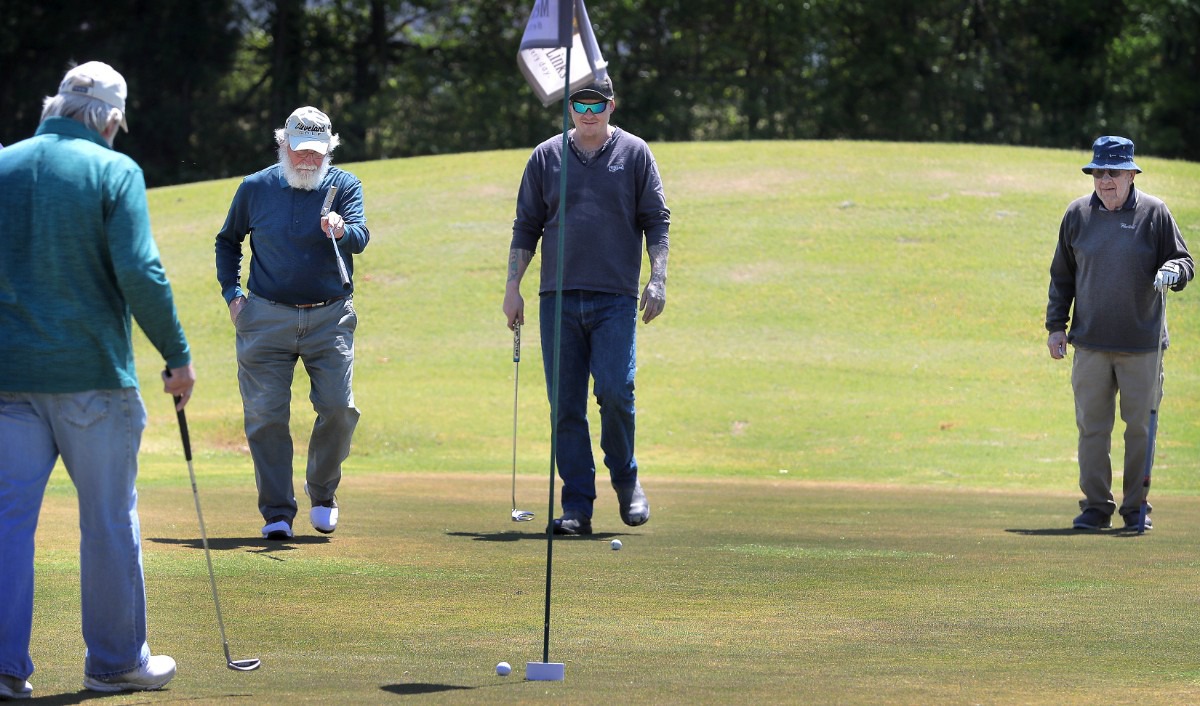 <strong>Lou Albonetti (second from left) reacts to a missed putt while Don Bumpous (left), Michael Kruckman and Bill Sheppard (right) watch from the edge of the green as golfers return to the Links at Whitehaven golf course on April 18, 2020, on a trial basis to test whether golfers would adhere to social distancing requirements during play. Only one person was permitted per cart and golfers were not allowed to handle the flag.</strong> (Jim Weber/Daily Memphian)