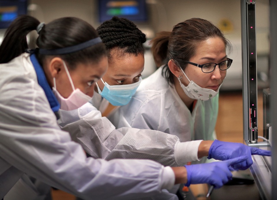 <strong>Medical technicians Jasmine Becton (left), Calisha Beauregard and Lanthanh Nguyen train on a new piece of equipment between processing patient samples at UTHSC's Coronavirus testing lab in the Hamilton Eye Center on April 16, 2020. The lab which has ramped up its testing capacity with the addition of more equipment and staff.</strong> (Jim Weber/Daily Memphian)
