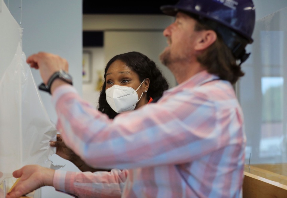 <strong>Nikki Gibbs (center) helps Bret James pull off the plastic from a piece of plexiglass that was installed into A Step Ahead foundation's Crosstown Concourse office April 27, 2020. Despite the pandemic some people and firms never stopped working.</strong> (Patrick Lantrip/Daily Memphian)