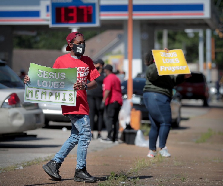 <strong>Stephen Snipes (left) and Sonja Jackson cheer for motorists lined up on James Road as volunteers from Golden Gate Cathedral, 100 Black Men of Memphis and other local groups come together on April 30, 2020, to give out free gas at the Marathon Station.</strong> (Jim Weber/Daily Memphian)