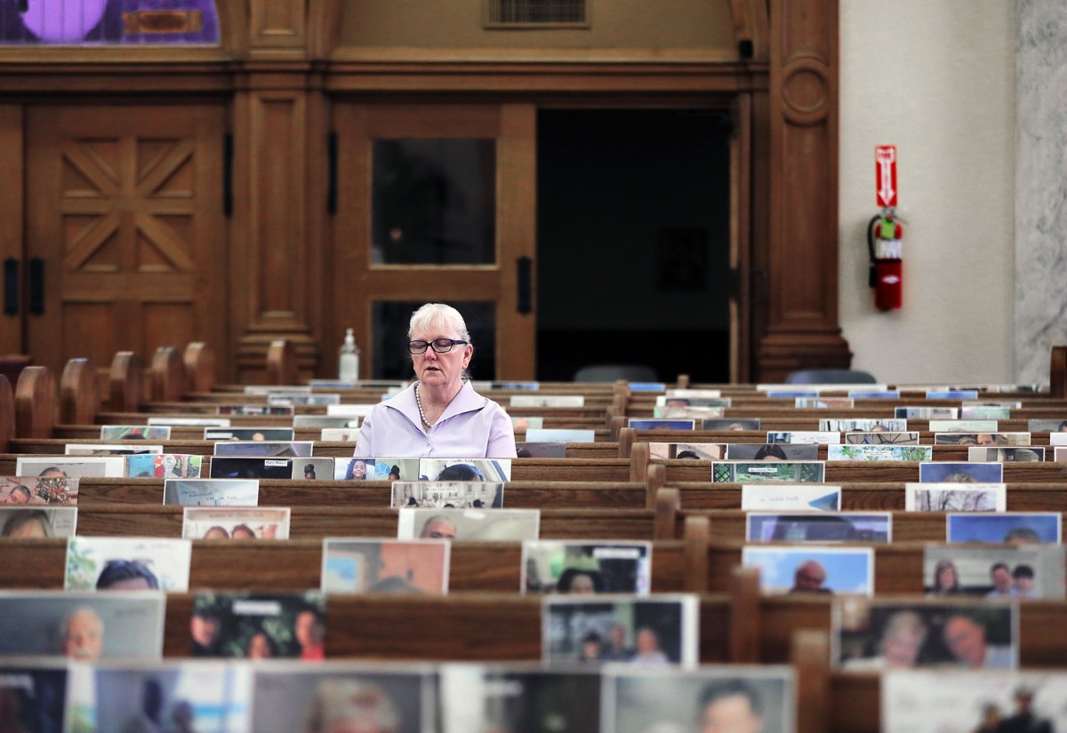 <strong>Bambi Williams, wife of deacon Frank Williams, prays alone at St. Patrick Catholic Church May 3, 2020 while surrounded by the photos of her fellow parishioners. The photos were hung as a way to make the church seem not as empty during its virtual services held during the COVID-19 pandemic.</strong> (Patrick Lantrip/Daily Memphian)