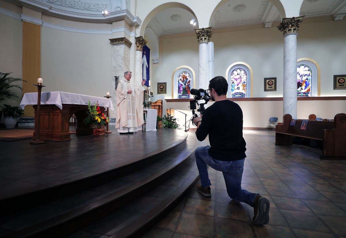<strong>Brody Kuhar films Monsignor Val Handwerker during a virtual mass at St. Patrick Catholic Church May 3, 2020.</strong> (Patrick Lantrip/Daily Memphian)