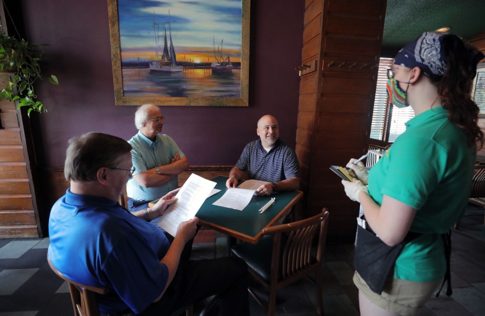 <strong>Half Shell employee Katelyn Pfahler takes the order of Jim Henry (from right), Dennis Russell and Wally Alexander on May 4, 2020.</strong> (Patrick Lantrip/Daily Memphian)