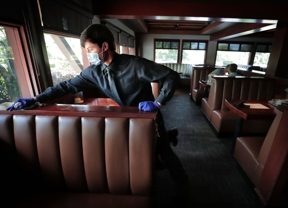 <strong>Brandon Gibson disinfects booths and tables after they are vacated as staff and servers at J. Alexander's Redlands Grill get things going again at the Cordova restaurant, while trying to keep up with restrictions put in place because of COVID-19.</strong> (Jim Weber/Daily Memphian)