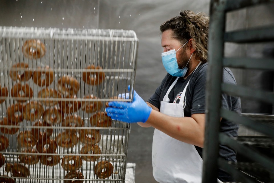<strong>Gibson&rsquo;s Donuts employee Matt Kennedy flips a rack of just-glazed old-fashioned donuts on Thursday, May 14. Gibson's, which closed in late March due to the COVID-19 pandemic, will reopen on Friday, May 15.</strong> (Mark Weber/Daily Memphian)