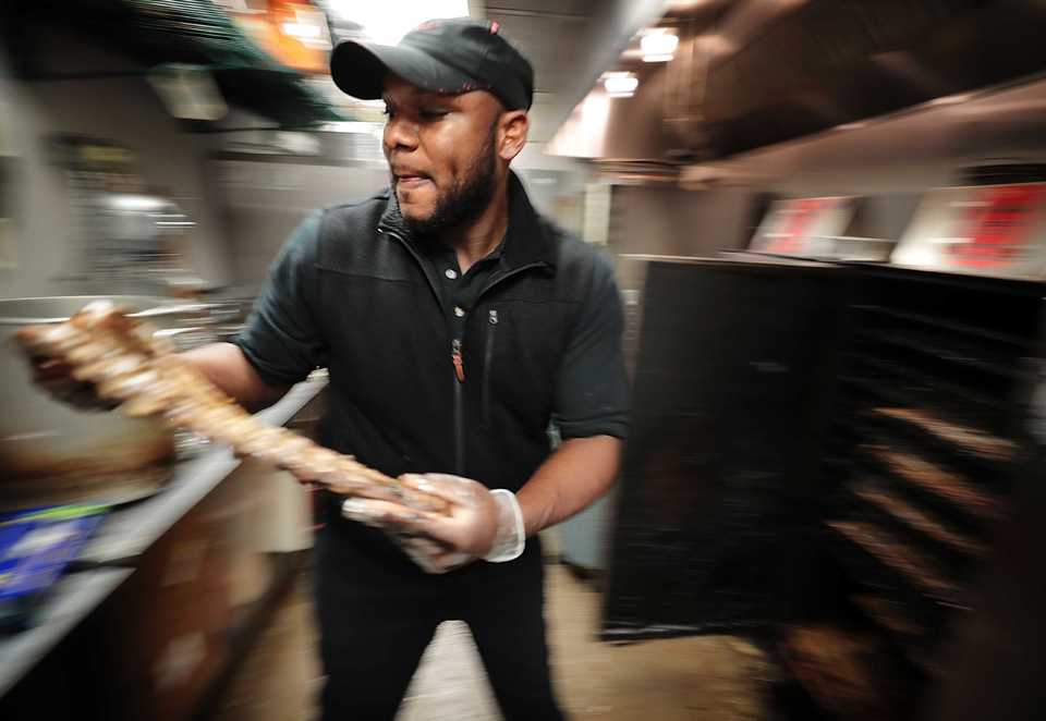 <strong>Prince Amoateng pulls ribs off the smoker at the busy One &amp; Only BBQ restaurant in Cordova during the lunch rush on Nov. 29, 2018. The Memphis-based chain is preparing to open its fourth restaurant in Southaven.</strong> (Jim Weber/Daily Memphian)