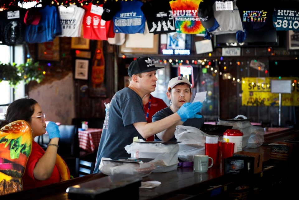 <strong>Huey&rsquo;s employees Chris Featherstone (left) and Jake Hamsley prepare to-go orders on April 2, at the Midtown location. The restaurant reopens its dining room at 11 a.m. on Wednesday, May 20.</strong> (Mark Weber/Daily Memphian)