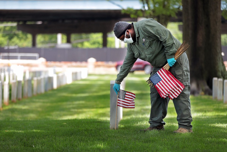 <strong>Army veteran and Memphis National Cemetery employee Howard Hurst places American flags near the gravesites of fallen service members on May 22, 2020, in preparation for Memorial Day.&nbsp;There will be no public events at the cemetery off Jackson Avenue this year</strong>. (Patrick Lantrip/Daily Memphian)