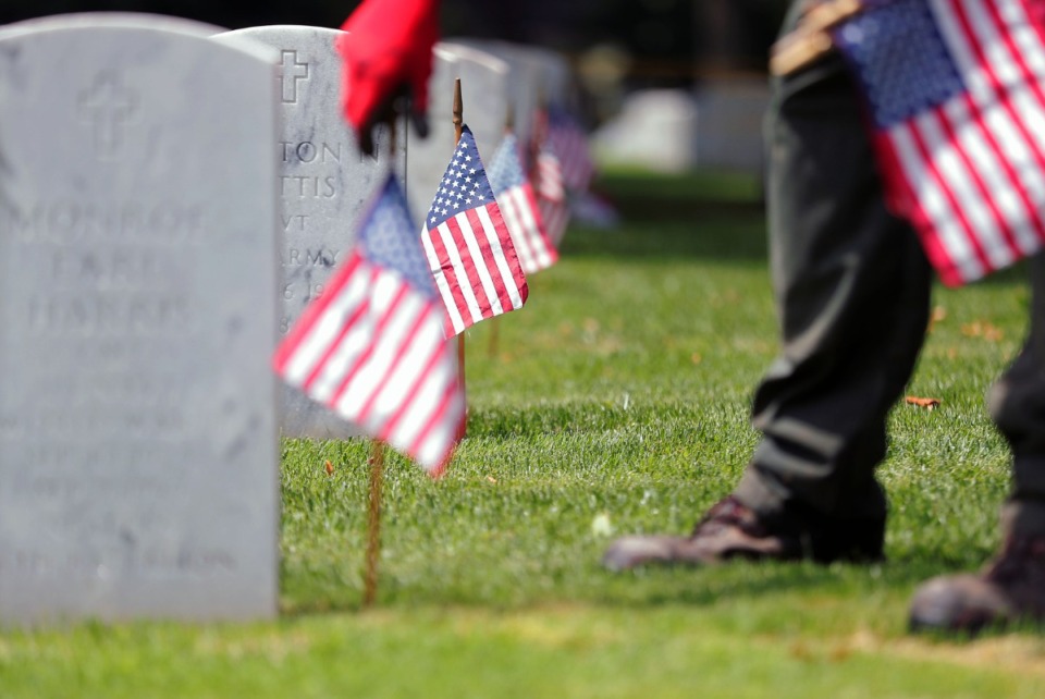 <strong>U.S. Navy veteran Michael Sinnock places American flags near the gravesites of fallen service members at the Memphis National Cemetery May 22, 2020, in preparation for Memorial Day.</strong> (Patrick Lantrip/Daily Memphian)
