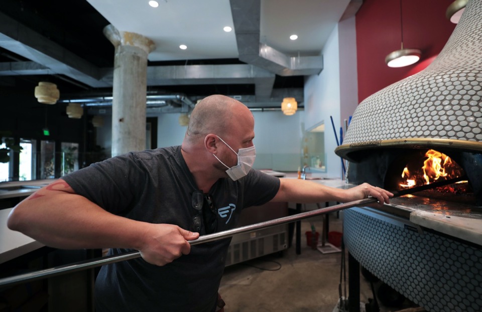 <strong>Brian Bazar tends to the fire at Pizzeria Trasimeno at the Crosstown Concourse May 29, 2020.</strong> (Patrick Lantrip/Daily Memphian)