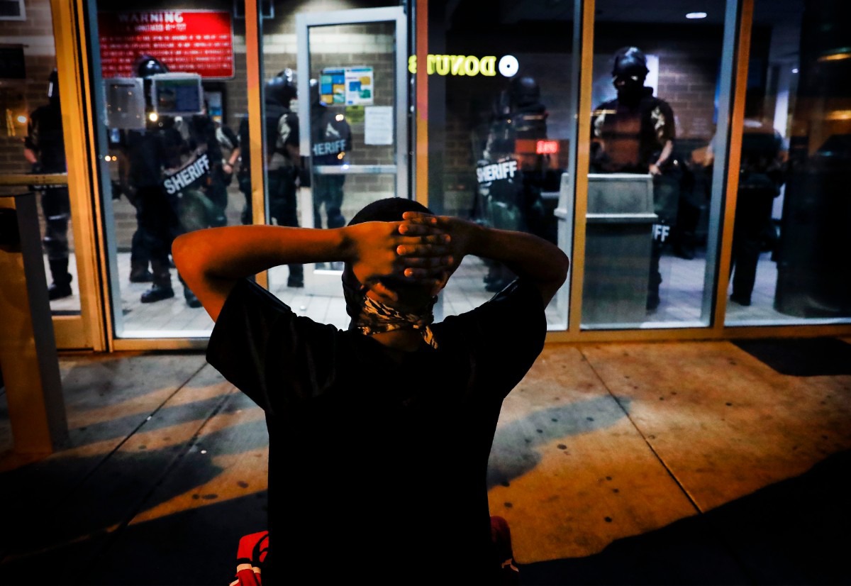<strong>A protester kneels in front of Memphis Police officers, who are inside the Shelby County Criminal Justice Center in Memphis on Monday, June 1, 2020, during a protest over the Minneapolis killing of George Floyd.</strong> (Mark Weber/Daily Memphian)