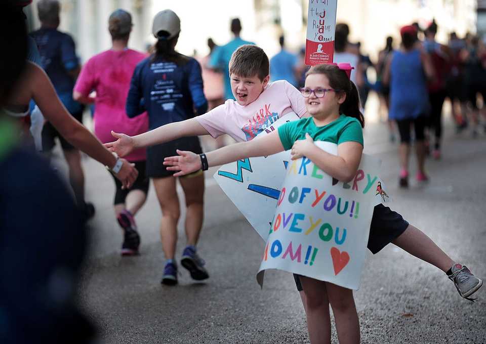 <strong>Kate Jackson, 7, and Sawyer Jackson, 8, high-five passing runners during the 17th annual St. Jude Memphis Marathon on Saturday, Dec. 1, 2018.Despite two rain delays, more than 26,000 runners participated in the charity event, raising over $11 million for young cancer patients.</strong>(Jim Weber/Daily Memphian)