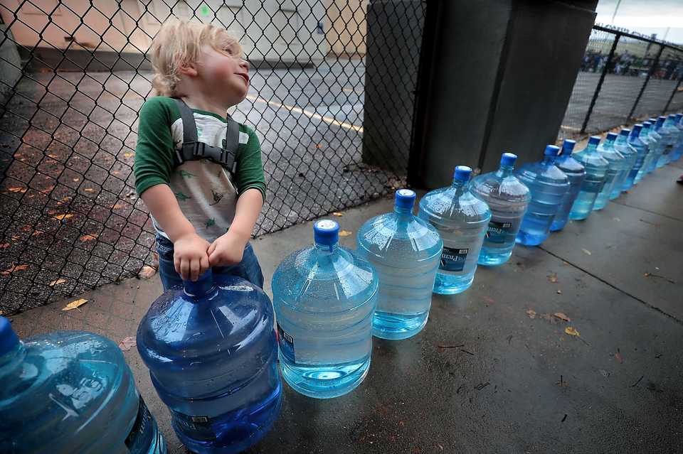 <strong>Two-year-old Julian Michael tries to heft one of the backup water bottles at a hydration station during the 17th annual St. Jude Memphis Marathon on Saturday, Dec. 1, 2018.Despite two rain delays, more than 26,000 runners participated in the charity event, raising over $11 million for young cancer patients.</strong>(Jim Weber/Daily Memphian)