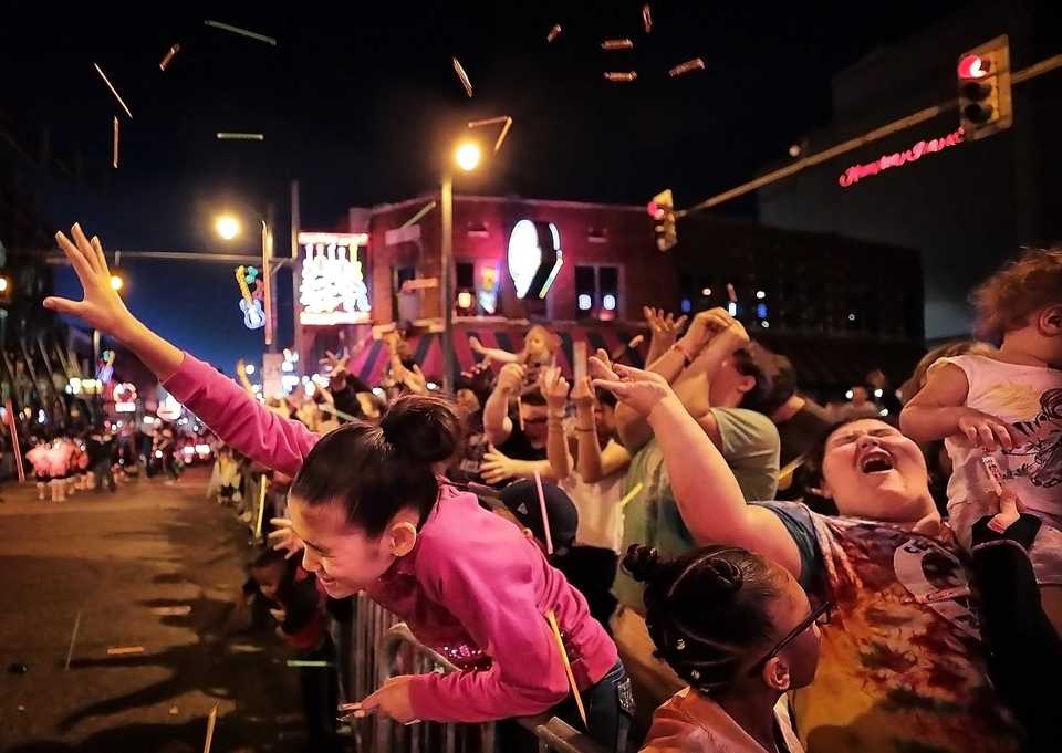 <strong>Aurora Roberts, 11, reaches blindly for treats as she is pelted with flying candy during the 2018 Memphis Holiday Parade on Beale Street on Dec. 1.Though the parade was delayed due to the late-running St. Jude Memphis Marathon that took place Saturday Downtown, it didn't deter thousands of Memphians from lining Beale to watch dancers, bands, floats, motorcycles and Santa usher in the holiday season. </strong>(Jim Weber/Daily Memphian)