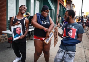 <strong>During a Defund the Police Block Party, while holding portraits of people killed at the hands of the police around the country, Kylan Miller (left) dances with Shannon Franklin, (middle) and twin brother Kameron Miller on Wednesday, June 10, 2020, on South Main.</strong> (Mark Weber/Daily Memphian)