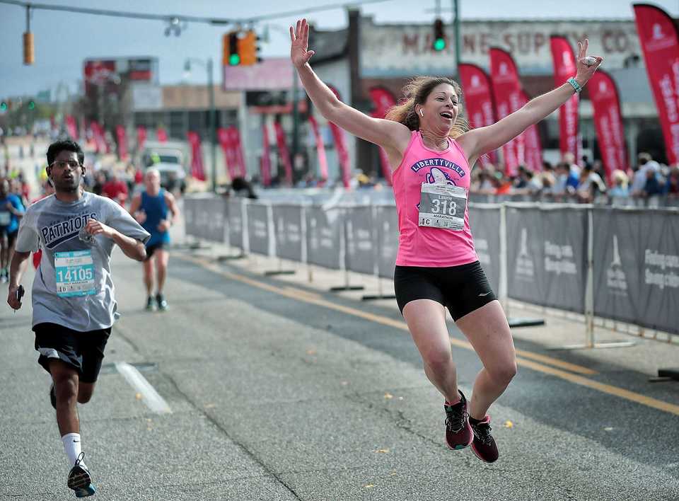 <strong>Laurie Scafidi leaps over the finish line during the 16th annual St. Jude Memphis Marathon on Saturday Dec. 1, 2018. Despite two rain delays, over 26,000 runners participated in the charity event raising over $11 million for young cancer patients.</strong> (Jim Weber/Daily Memphian)
