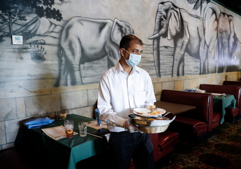 <strong>India Palace owner Binder Kumar clears a table during lunch on Wednesday, June 10. Kumar has made it&nbsp;mandatory to wear a mask in his restaurant, and said he hasn&rsquo;t had any complaints.&nbsp;&ldquo;... They understand that it&rsquo;s just good for everyone to wear the mask,&rdquo; he said.</strong> (Mark Weber/Daily Memphian)