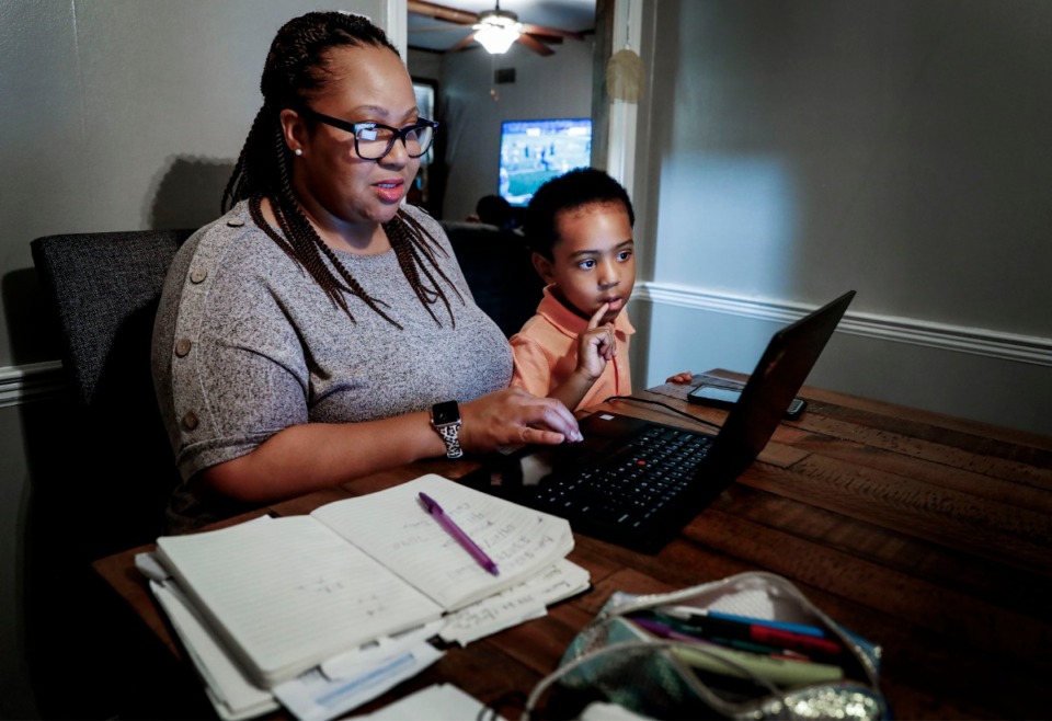 <strong>Eureka Duckett (left) gets a visit from her son Dallas, 3, while working in the family dining room on Wednesday, July 15, 2020. Before her husband, Develle, went back to work three weeks ago, they traded spending time with the children while the other one worked. Now she is on her own.</strong> (Mark Weber/Daily Memphian)
