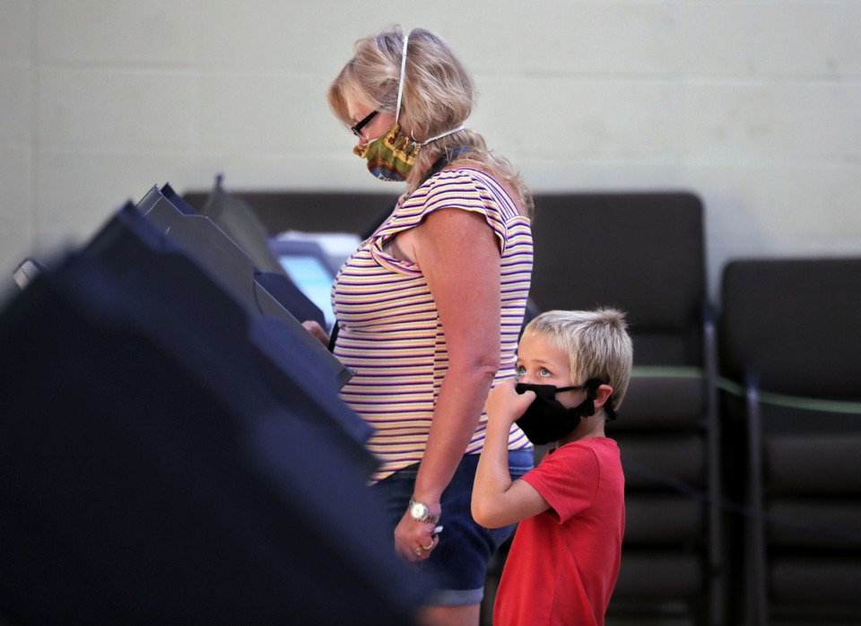 <strong>A child adjusts his mask as his mother votes in the primary election at Arlington United Methodist Church on Thursday, Aug. 6.</strong> (Patrick Lantrip/Daily Memphian)