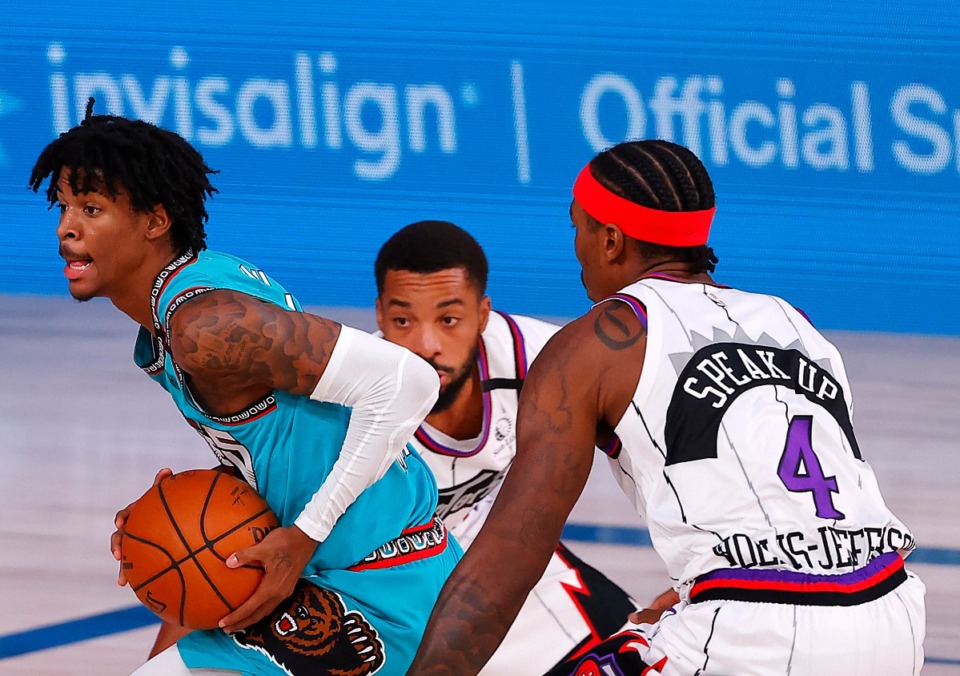 <strong>Memphis Grizzlies' Ja Morant, left, drives between Toronto Raptors' Rondae Hollis-Jefferson (4) and Norman Powell, center, during the second quarter of an NBA basketball game Sunday, Aug. 9, 2020, in Lake Buena Vista, Fla.</strong> (Kevin C. Cox/AP)
