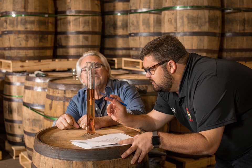 <strong>Ryan Trimm and Roger Sapp, partners in Across the Board restaurant group with Craig Blondis, study the hydrometer that tests the proof of their bourbon.</strong> (Photo by Justin Fox Burks, courtesy of Sweet Grass)