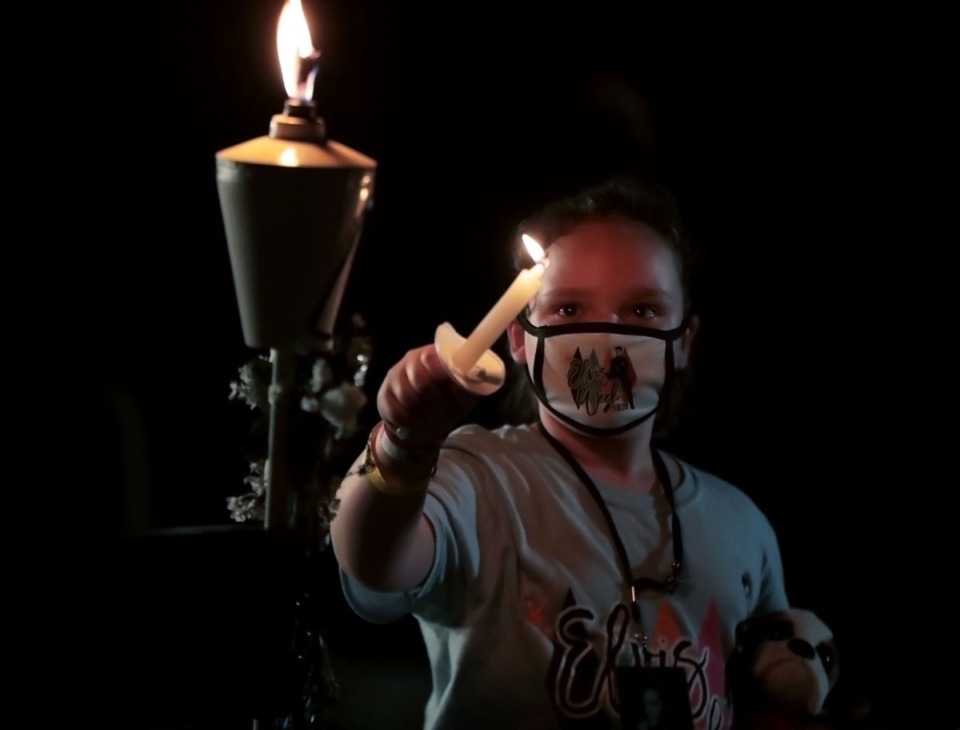 <strong>A child lights a candle at Graceland in remeberce of Elvis Presley during a socially distanced candlelight vigil Aug. 15, 2020.</strong> (Patrick Lantrip/Daily Memphian)