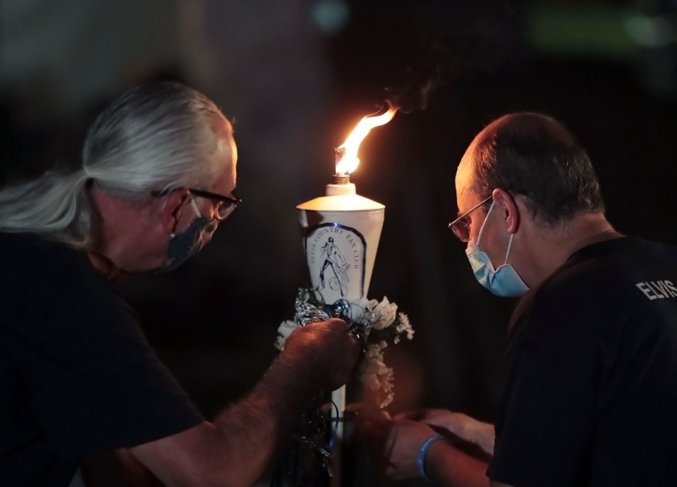 <strong>Two Graceland employees light the main flame from which guests will ignite their individual candles during Graceland's candlelight vigil Aug. 15, 2020.</strong> (Patrick Lantrip/Daily Memphian)