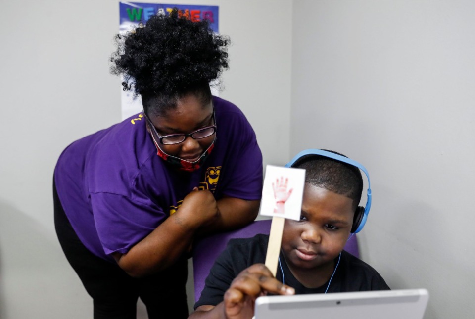 <strong>New Life Learning Academy volunteer Kirby Wesson (left) works with her son Kayden Nolen, 7, a second grader at Oak Forest Elementary, to get his teacher&rsquo;s attention on Monday, Aug. 31, 2020. The academy made space for the children of employees and siblings of younger children enrolled at the daycare, to provide a safe space for students attending the first day of school virtually due to the COVID-19 pandemic. </strong>(Mark Weber/Daily Memphian)