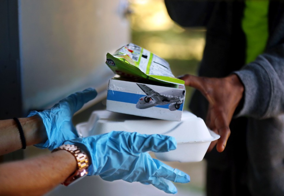 <strong>Volunteer Gretchen Hollingsworth hands out a warm meal, a donated FedEx &ldquo;pilot pack&rdquo; and a bag of chips outside of the Society of St. Vincent de Paul at the Ozanam Center Nov. 6, 2020.</strong> (Patrick Lantrip/Daily Memphian)