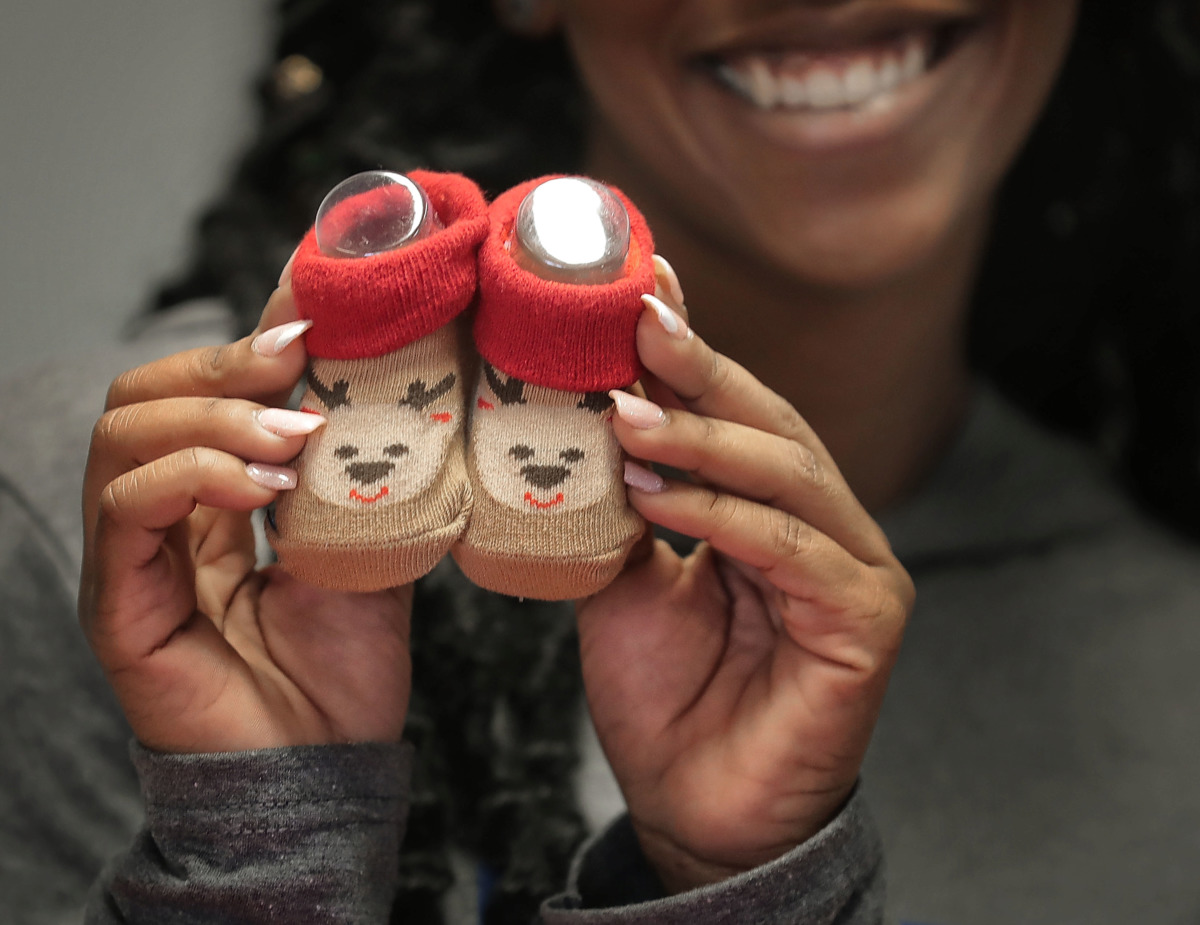 <strong>Sandi Sadler with the Office of Youth Services shows off a pair of baby booties as youths with the Memphis Ambassadors Program sort through winter wear collected during their charity coat drive. MAP collected more than 1,200 clothing items to distribute to needy kids at Memphis community centers, Meritan foster care and area schools.</strong> (Jim Weber/Daily Memphian)