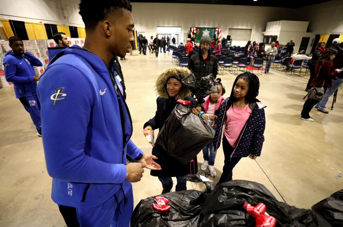 <strong>Antwann Jones (left), a guard for the University of Memphis basketball team, hands a bag of Christmas gifts to Jordan Brunson (center) during a toy drive hosted by the University of Memphis and the City of Memphis.</strong> (Houston Cofield/Daily Memphian)