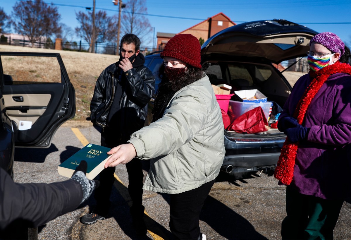 <strong>Lunches &rsquo;N Love outreach ministries&rsquo; founder Sydney Crabtree (middle) hands out a Bible while giving donated supplies to the needy on Friday, Dec. 25, 2020 around Downtown.</strong> (Mark Weber/The Daily Memphian)