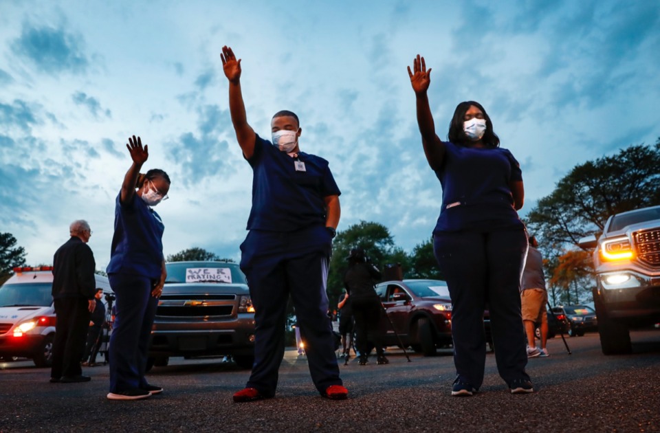 <strong>St. Francis Hospital-Memphis nurses, including Deonta Buck (middle), raise their hands in praise while attending a prayer vigil for patients and staff in the hospital parking lot on Monday, April 6, 2020</strong>. (Mark Weber/Daily Memphian)