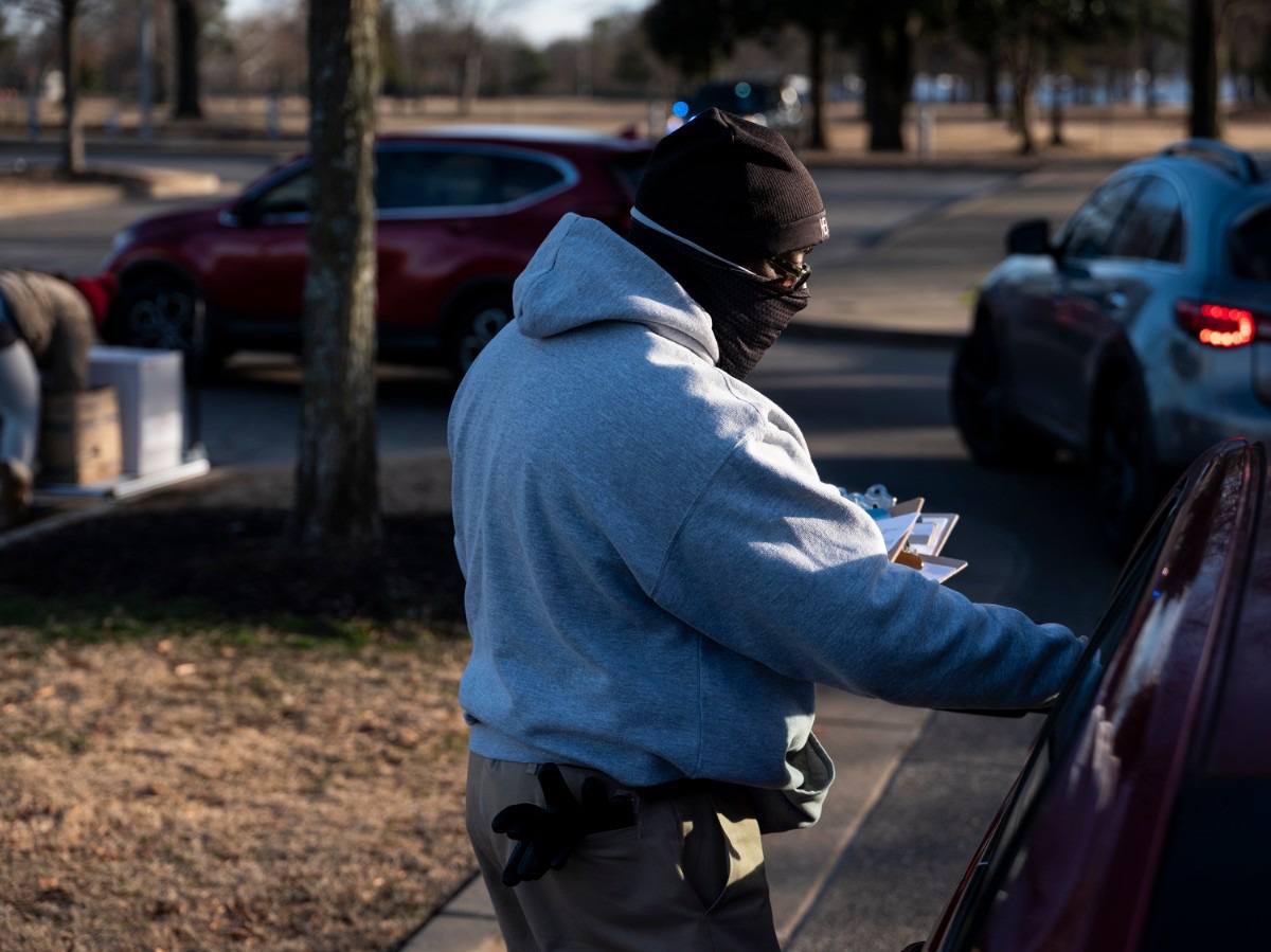 <strong>McKinley Wallace hands out forms to people waiting to receive the COVID-19 vaccine inside the Pipkin Building, Friday, Jan. 29, 2021.</strong> (Brad Vest/Special to The Daily Memphian)