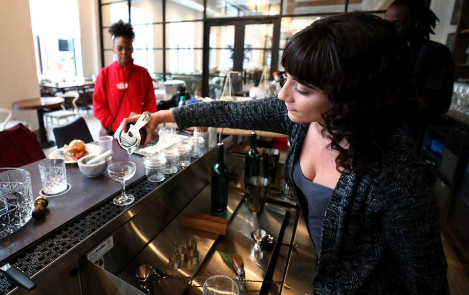 <strong>Alexandra Barnes, a bartender at The Greyhound inside the Hilton Garden Inn Memphis Downtown, practices serving drinks from the bar's menu. The hotel, which is set to open Thursday, Jan. 17, 2019, pays homage to the site's past as a Greyhound bus station.</strong> (Houston Cofield/Daily Memphian)