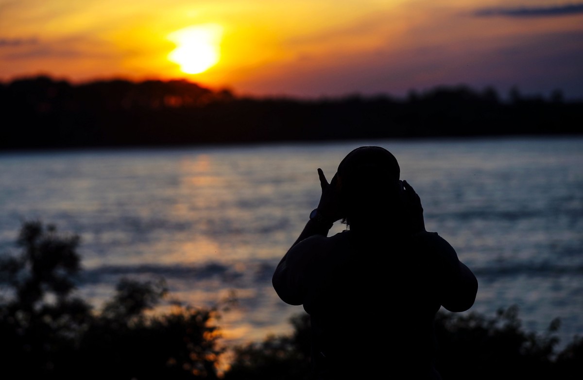 <strong>Sasha Taylor takes a picture of the sunset over the Mississippi River.</strong> (Patrick Lantrip/Daily Memphian)