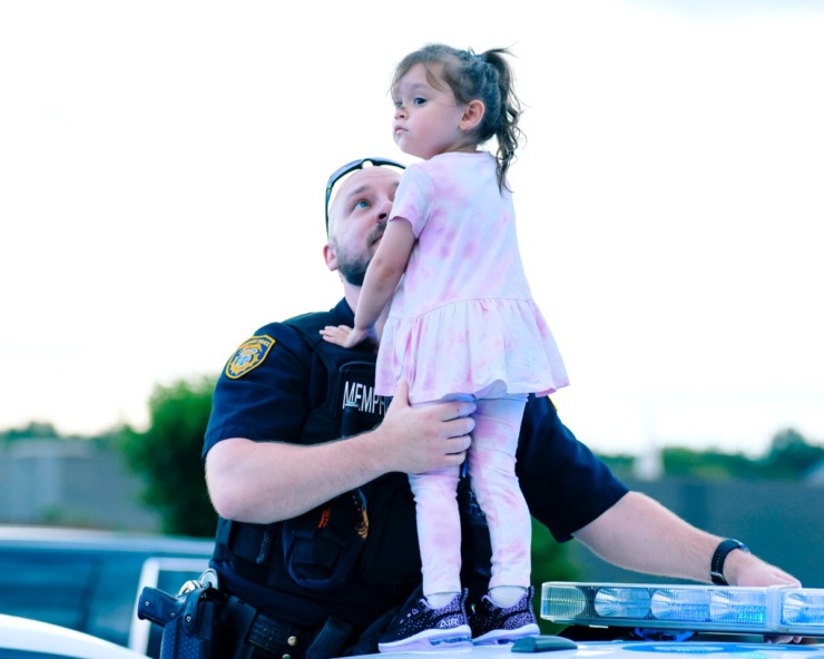 <strong>Officer David Osborn holds his daughter Juliet on top of his police car as they survey the blue lights from hundreds of police cars gathered for the Sea of Blue ceremony at Hope Presbyterian Church. Hundreds of police officers across Shelby County gathered in the parking lot prior to driving a 40-mile route around Memphis in honor of officer Christopher Scott &ldquo;Scotty&rdquo; Triplett. Triplett was killed last week after he was struck by a car while riding his motorcycle in a motorcade near Hickory Hill.</strong>(Houston Cofield/Special To The Daily Memphian)