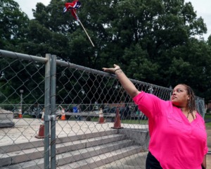 <strong>Shelby County Commissioner Tami Sawyer removes a Confederate flag hanging from the fence surrounding the grave of Nathan Bedford Forrest June 1, 2021.</strong> (Patrick Lantrip/Daily Memphian)