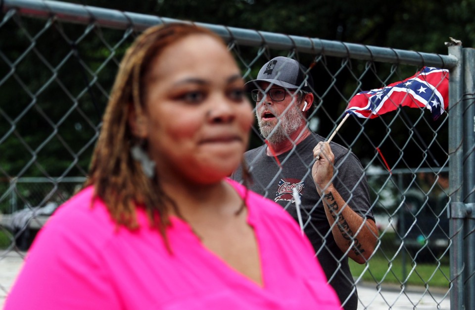 <strong>A man who identified himself as K-Rack Johnson sings "Dixie" while waving a Confederate flag behind Shelby County Commissioner Tami Sawyer during the June 1 press conference in Health Sciences Park.</strong> (Patrick Lantrip/Daily Memphian)