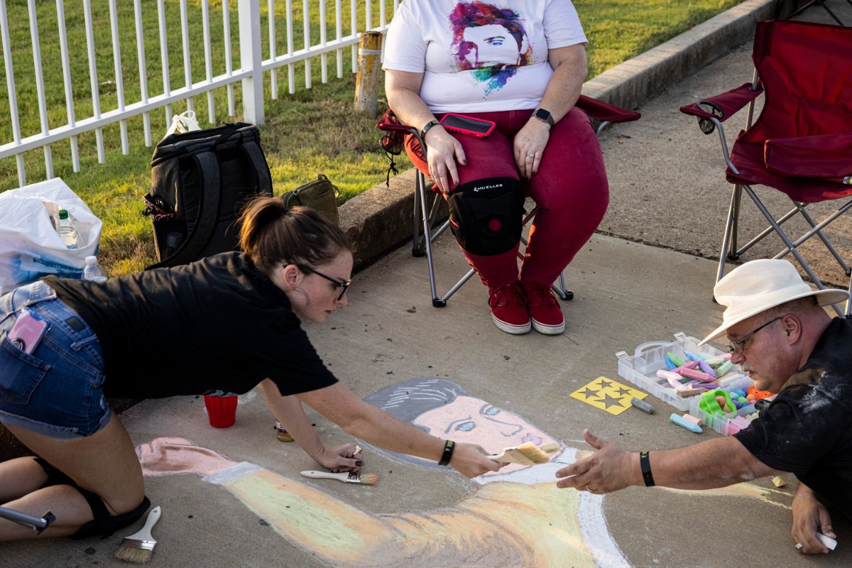 <strong>Haley Damron (left) passes a brush to her father, Greg Damron, while creating sidewalk art along Elvis Presley Boulevard during the Elvis Week Candlelight Vigil, Sunday, Aug. 15, 2021.</strong> (Brad Vest/Special to The Daily Memphian)
