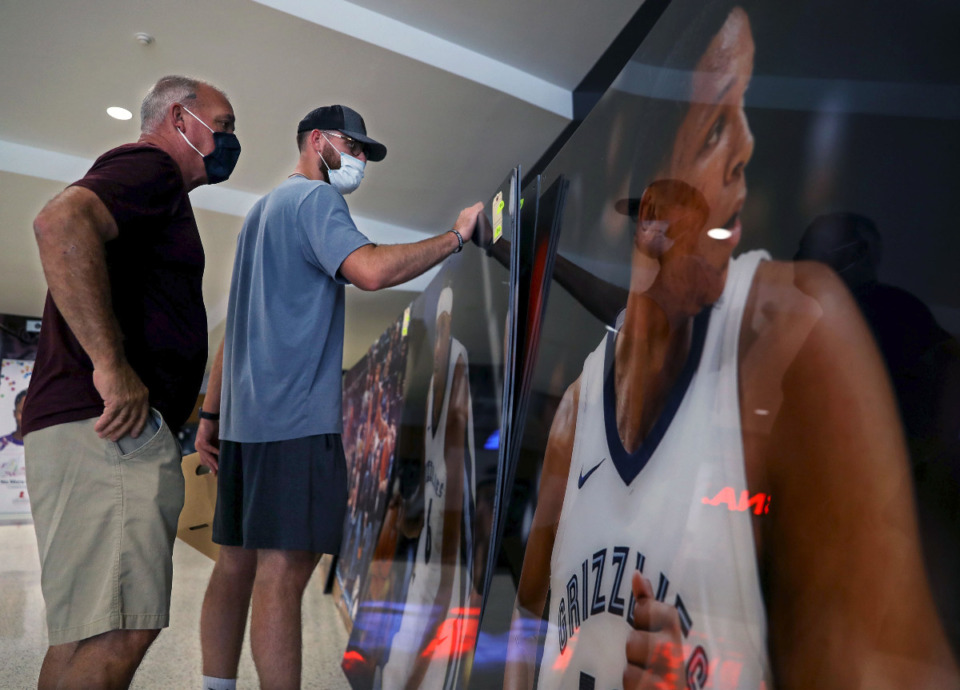 <strong>Deno Harrison (left) and his son Skyler look through a stack of giant posters for sale at the Grizzlies Garage Sale at the FedExForum Aug. 28, 2021.</strong> (Patrick Lantrip/Daily Memphian)