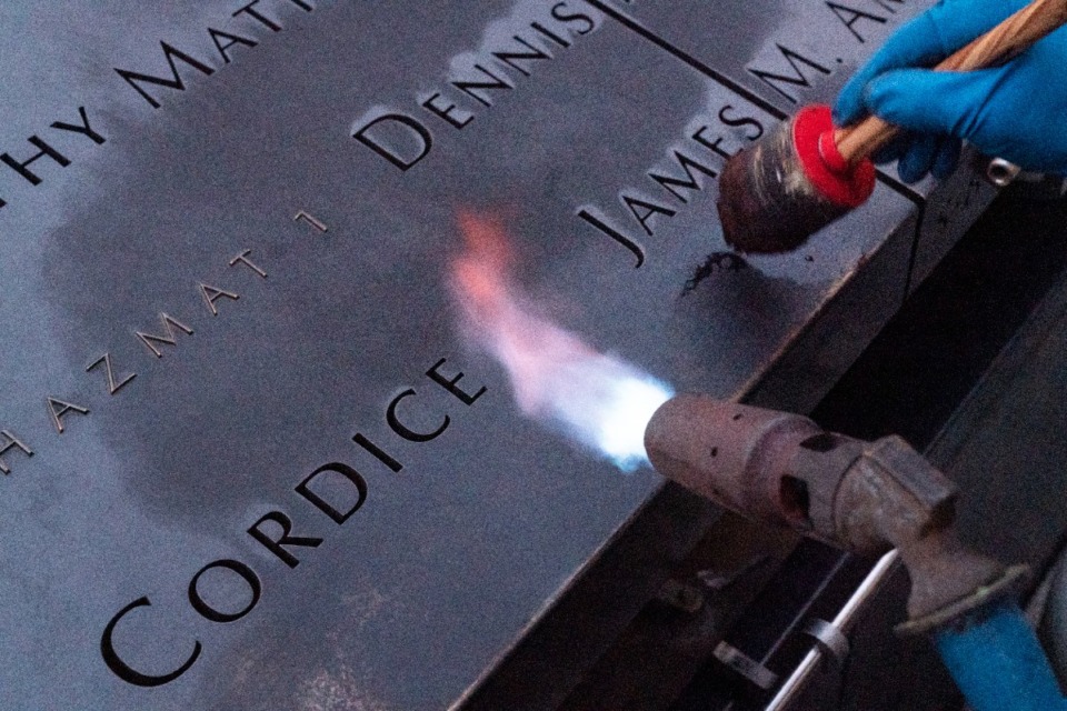 <strong>Kevin Hansen, an engineer at the September 11 Memorial, uses a torch to clean and burnish the names cut into the metal plates that border the south pool.</strong> (Mark Lennihan/AP)