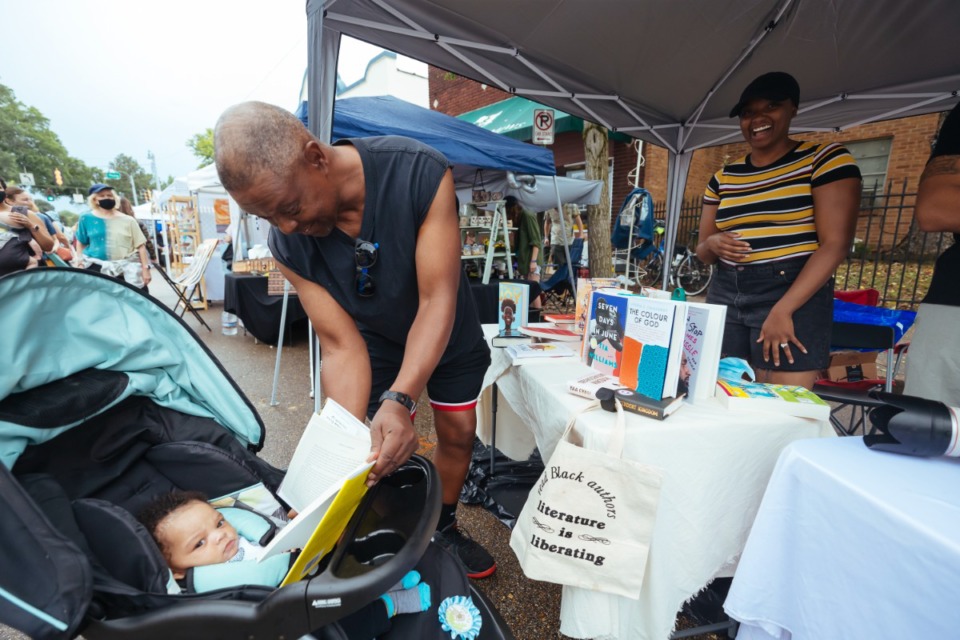 <strong>Darryl Freeman shows his grandson books from the Cafe Noir Bookstore booth.</strong> (Ziggy Mack/Special to The Daily Memphian)