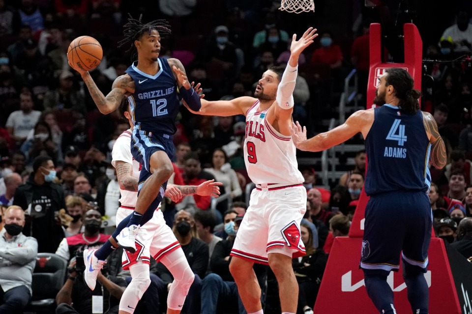<strong>Grizzlies guard Ja Morant (12) passes under pressure from Chicago&rsquo;s&nbsp;Nikola Vucevic (9) as Steven Adams watches on Oct. 15 in Chicago.</strong> (Charles Rex Arbogast/AP)