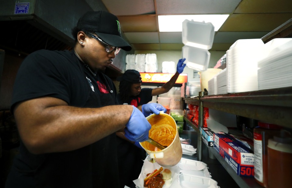 <strong>Tebious "T Bow" Archer stirs up Ching's Hot Wings' famous honey gold sauce as he prepares to pour it over the top of some whole wings. Restaurant owner Edgar Lafayette Williams says the honey gold is a favorite because of their in-house recipe.</strong> (Houston Cofield/Daily Memphian file)
