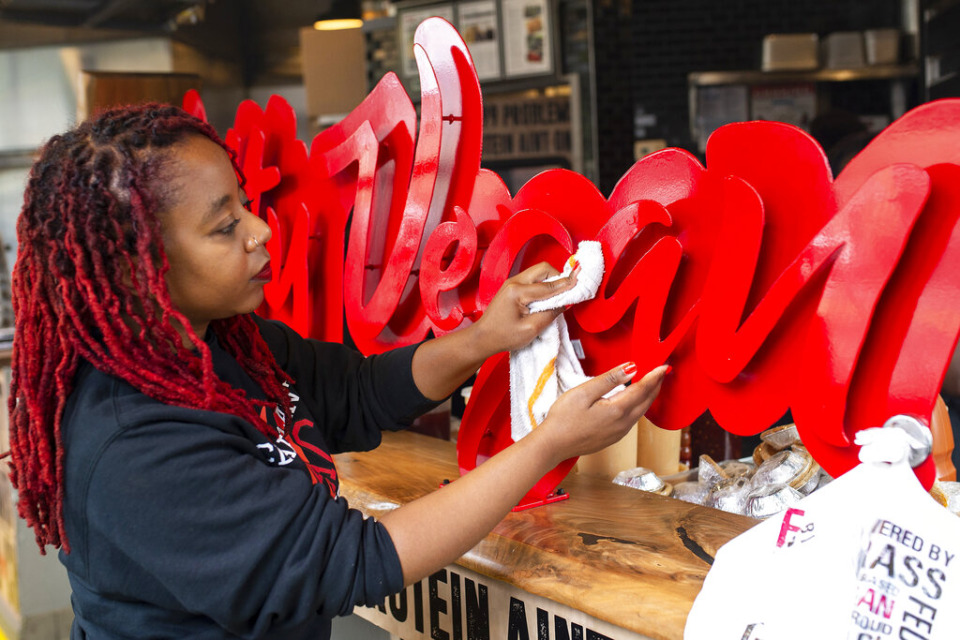 <strong>In this Wednesday, May 20, 2020, photo, Pinky Cole, owner of Slutty Vegan restaurants and food trucks, wipes down a sign on her storefront in Atlanta.</strong> (AP Photo/Angie Wang)