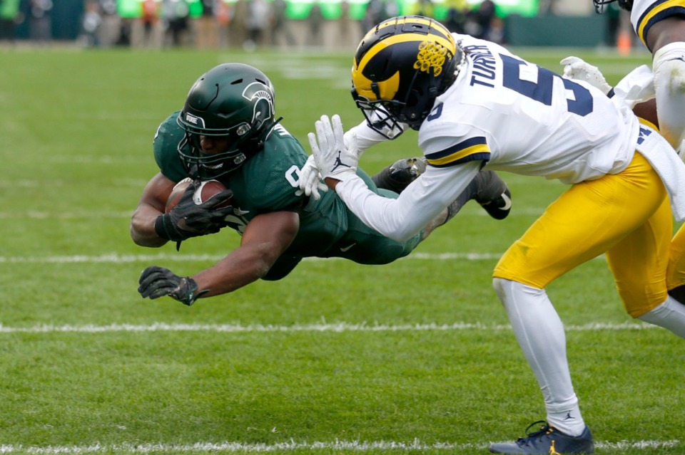 <strong>Michigan State's Kenneth Walker III, left, dives over the goal line for a touchdown against Michigan's DJ Turner during the second quarter of an NCAA college football game, Saturday, Oct. 30, 2021, in East Lansing, Mich.</strong> (AP Photo/Al Goldis)