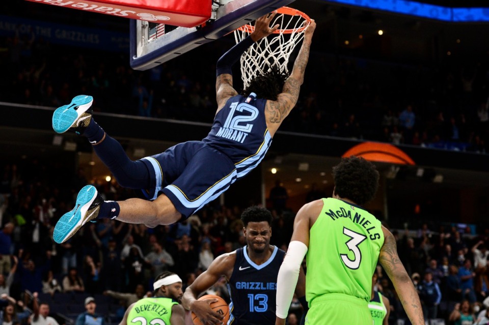 <strong>Grizzlies guard Ja Morant (12) hangs from the rim after dunking against Minnesota on Nov. 8 at FedExForum.</strong> (Brandon Dill/AP file)