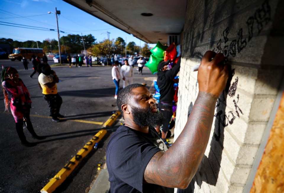 <strong>Terrance Whitelow writes his respects to Young Dolph on the wall of Makeda's on Thursday, Nov. 18, at a memorial at the site where the rapper was slain.</strong> (Patrick Lantrip/Daily Memphian)